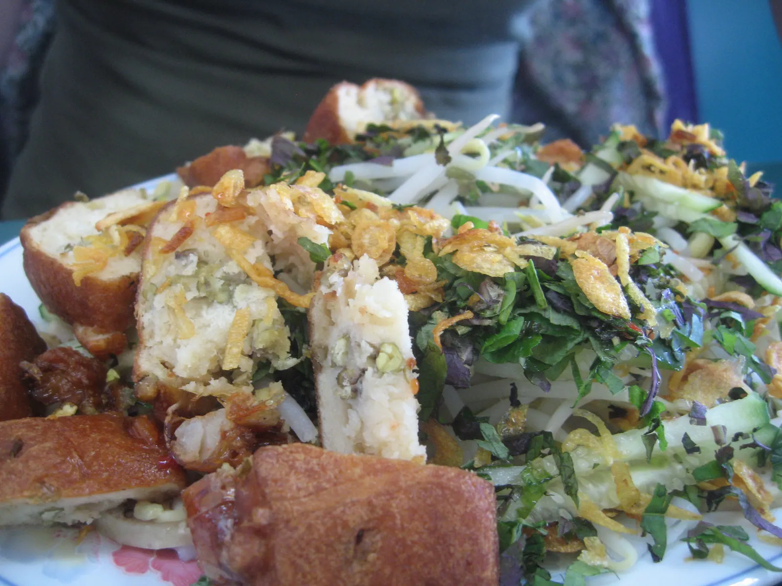 Soft steamed rice sheets, banh uot, served with slices of fried fish cake and herbs