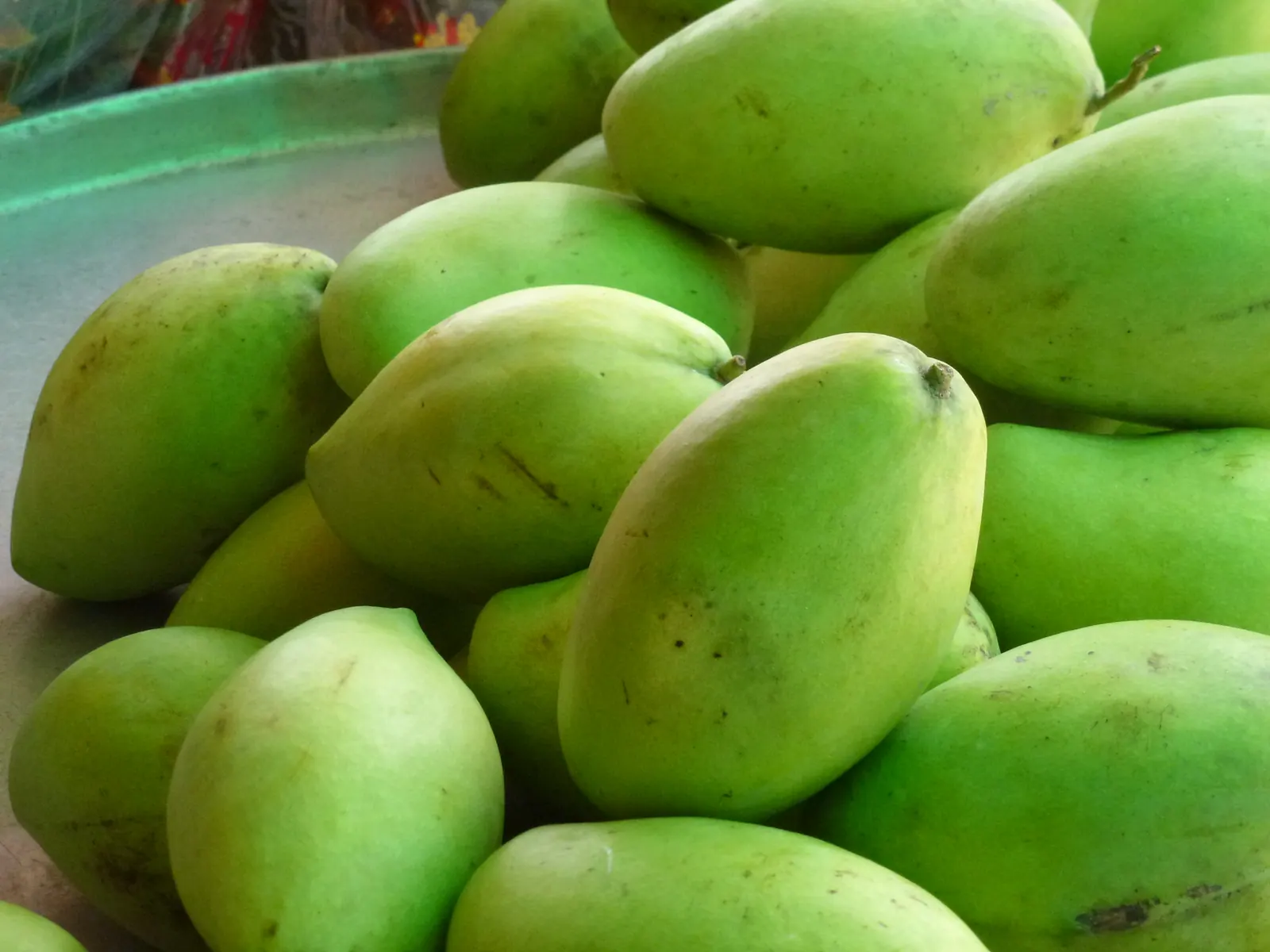 Green mangoes piled at a market stall