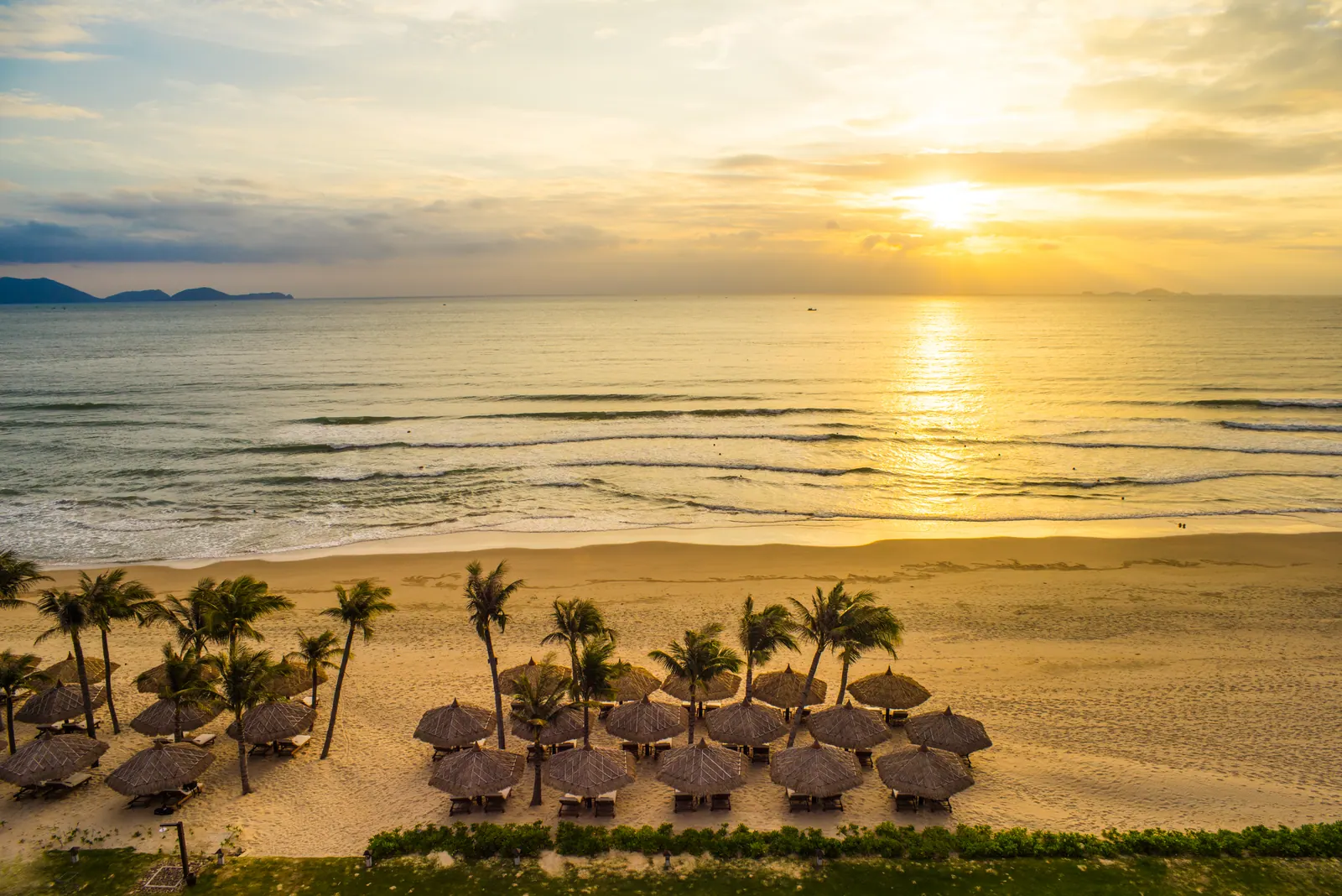 Bai Dai (Long Beach) on Cam Ranh bay: wide pale-sand beach and turquoise shallows backed by low green hills.