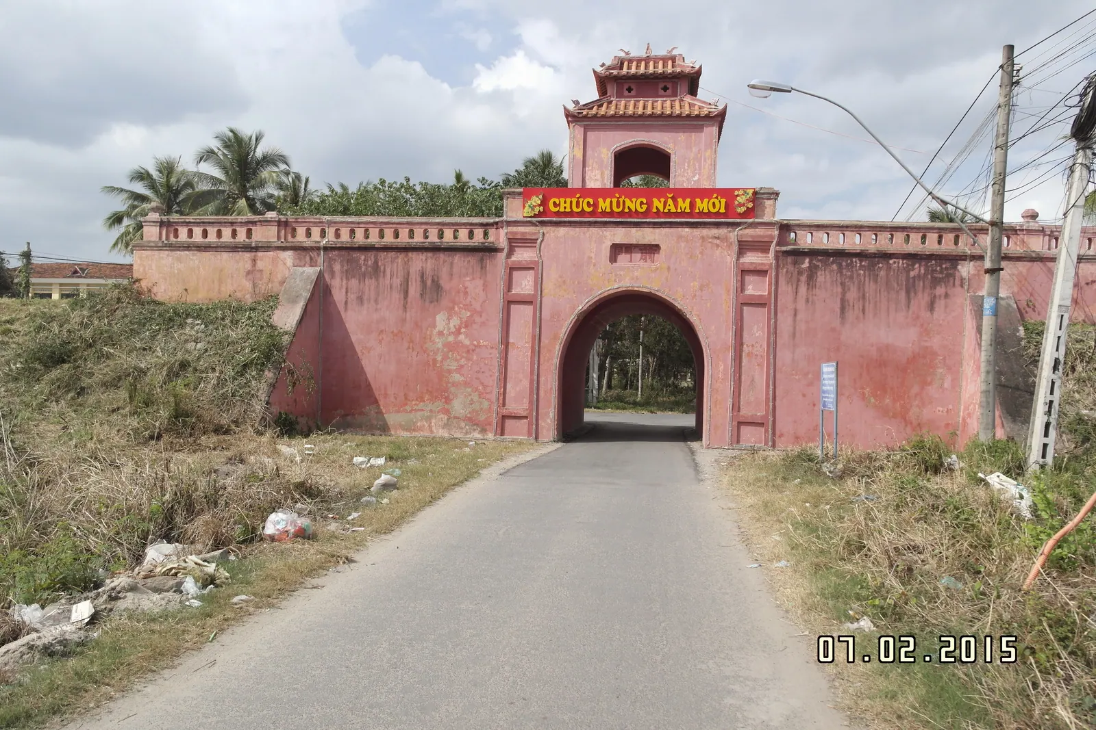 The red-painted east gate of the Dien Khanh citadel with its watchtower pavilion, seen from the approach road.