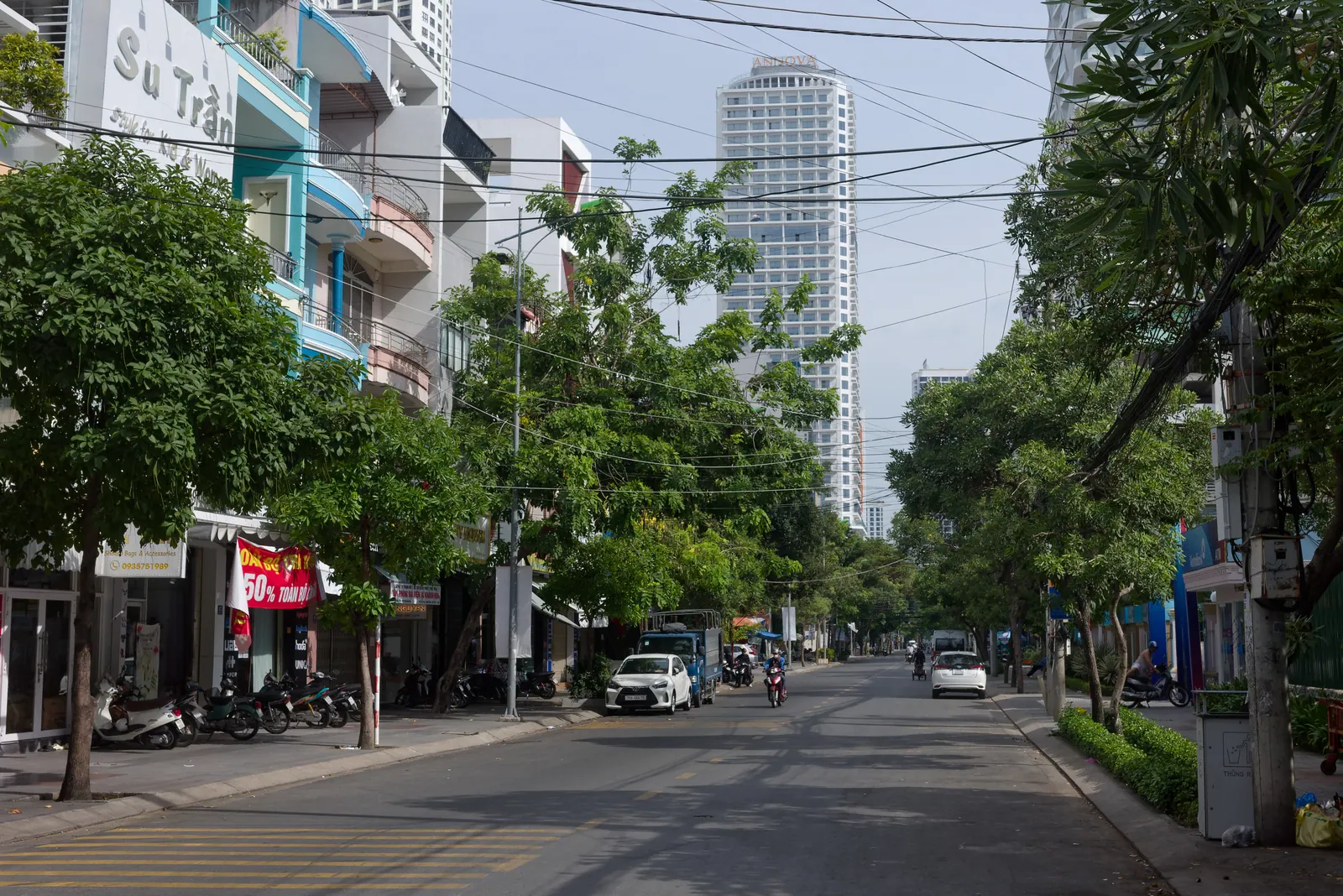 Tree-lined Hoang Hoa Tham street in Nha Trang with shophouses and parked motorbikes