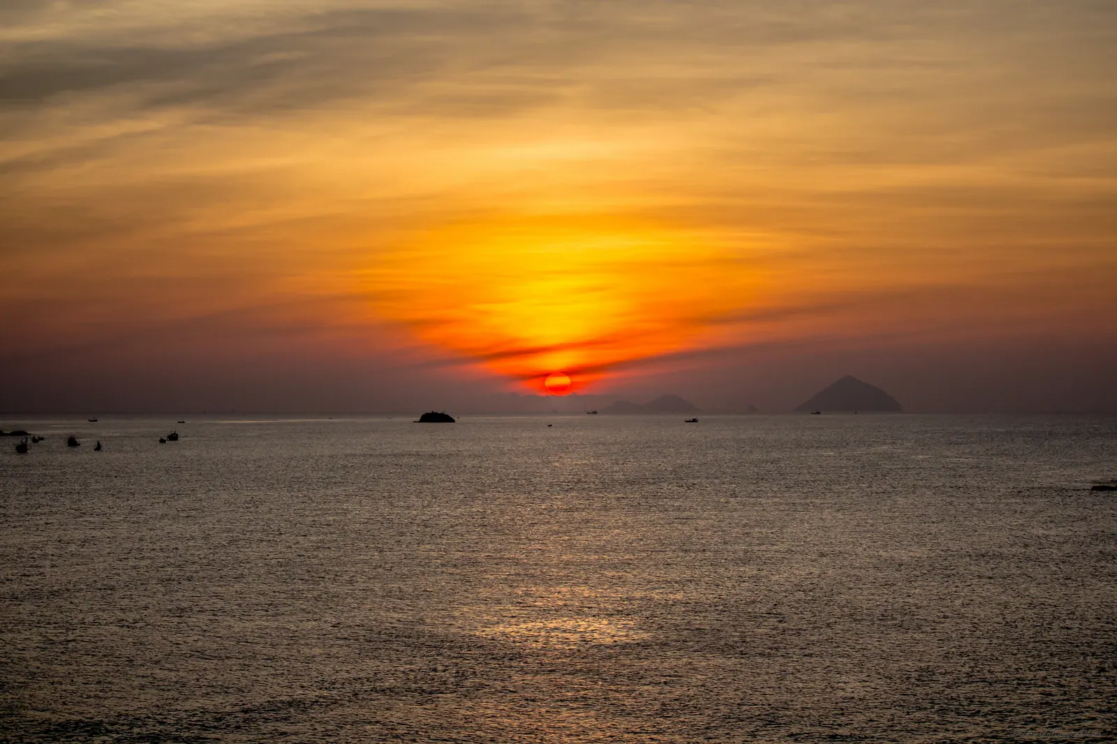 A red sun rising over the calm water of Van Phong bay.