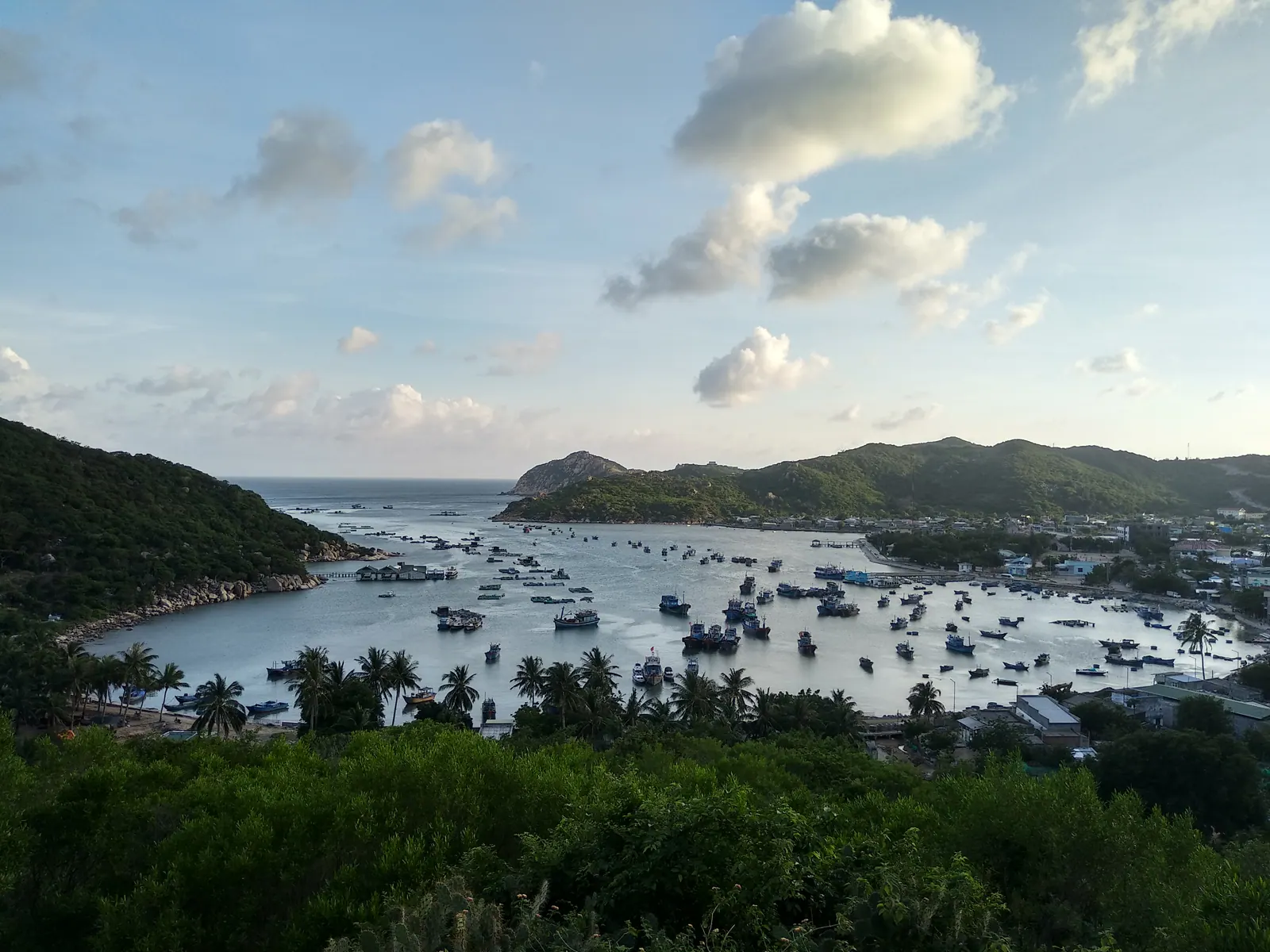 Vinh Hy Bay: fishing boats on flat green water ringed by the mountains of Nui Chua.